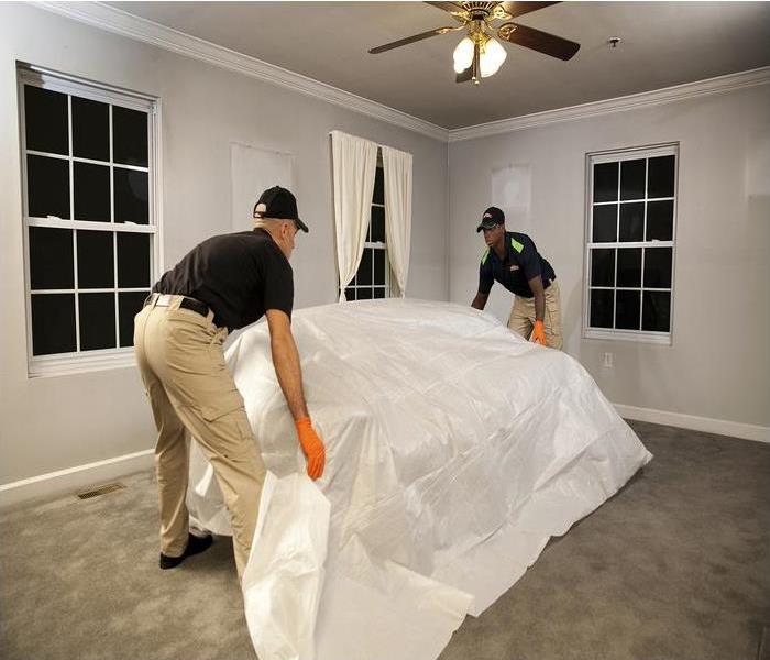 2 techs covering and moving a piece of furniture in a living room